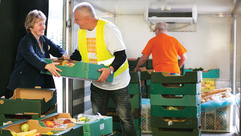 Colleagues lifting trays of fruit