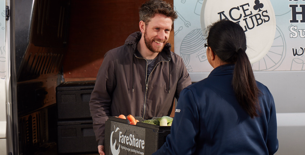 A Tesco colleague hands a Fareshare representative food that would otherwise have gone to waste
