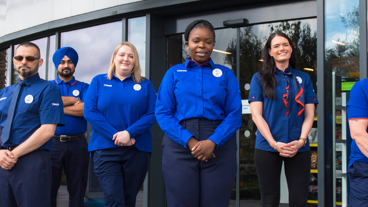 A group of Tesco colleagues standing smiling outside the store door