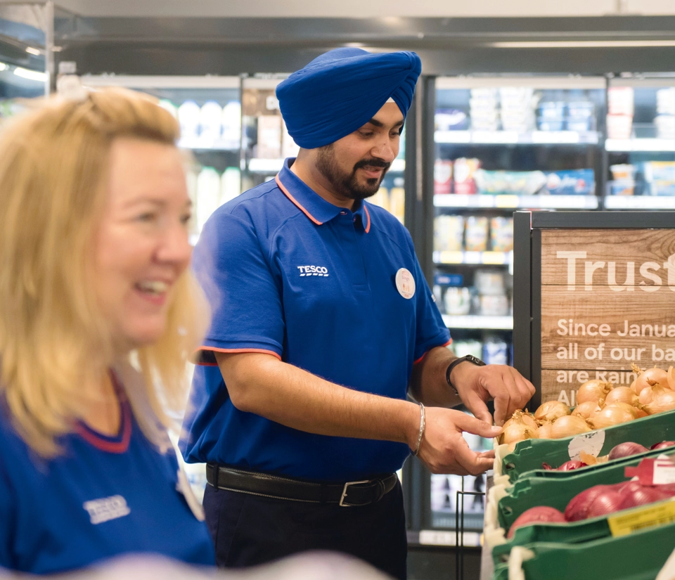 Two tesco workers, a man and a woman, smiling